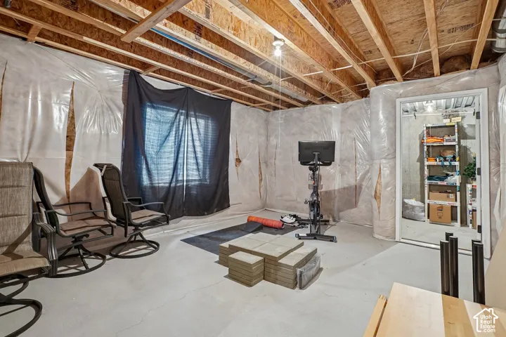 Unfinished basement space featuring exposed wood joists and concrete flooring