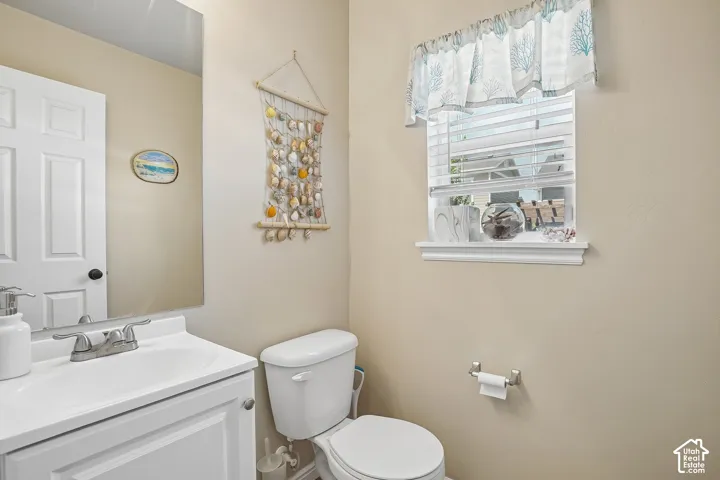 Bathroom featuring a single white vanity with an integrated sink, a two-handle chrome faucet, and a wall-mounted mirror
