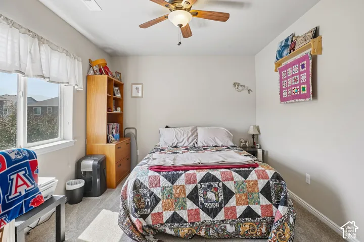 Carpeted room with a ceiling fan light fixture, a window with horizontal blinds, and a built-in wooden shelving unit with drawers