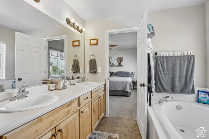 Double vanity with light wood cabinetry and integrated sinks, illuminated by a four-bulb fixture