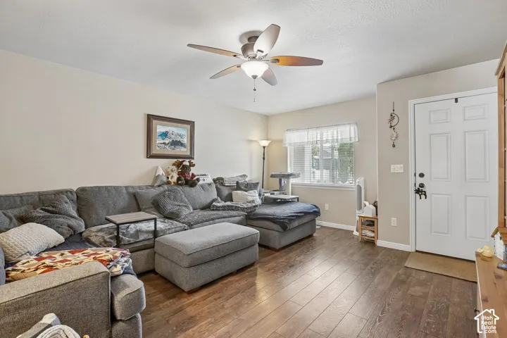 Open-concept living space with wood-finish flooring, a ceiling fan with integrated lighting, and neutral wall tones