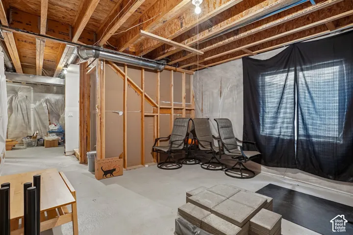 Unfinished basement featuring exposed wood joists, concrete flooring, and partial framing for future development