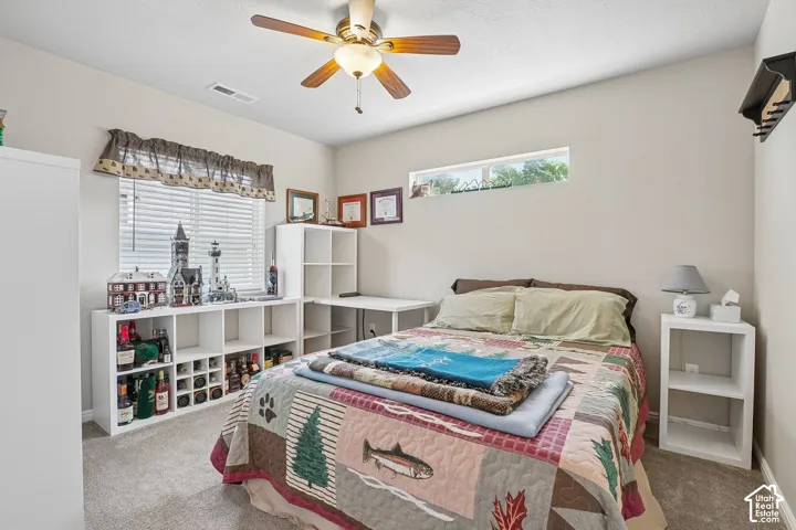 Bedroom featuring a ceiling fan with light fixture, carpeted flooring, and light-toned walls