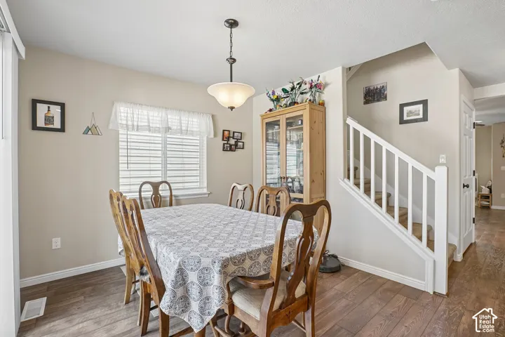 Dining area featuring wood-finish flooring, a contemporary ceiling light fixture, and a built-in display cabinet