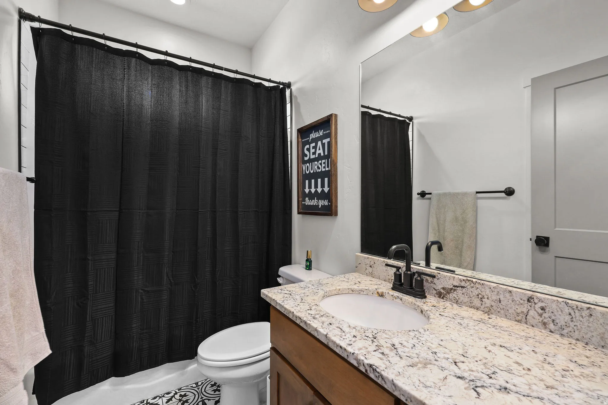 Bathroom vanity featuring a light-toned stone countertop, integrated sink, and dark-finish faucet