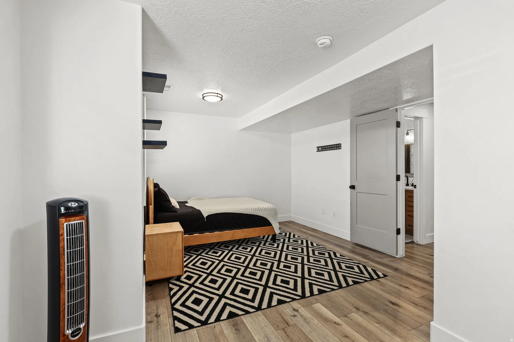 Room featuring wood-finish flooring, white walls, and a ceiling-mounted light fixture