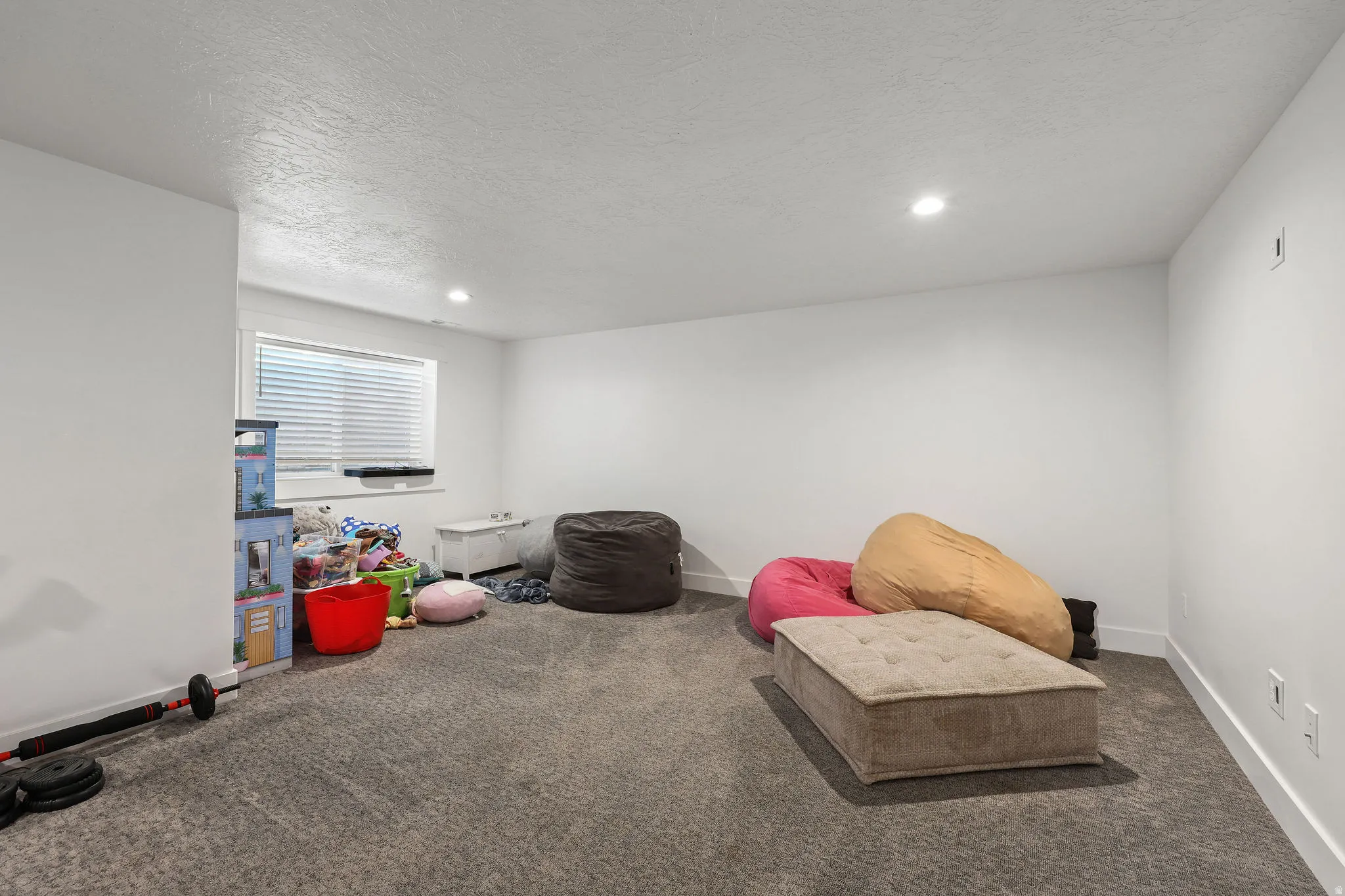 Spacious room featuring neutral carpeting, white walls, and a single window with blinds