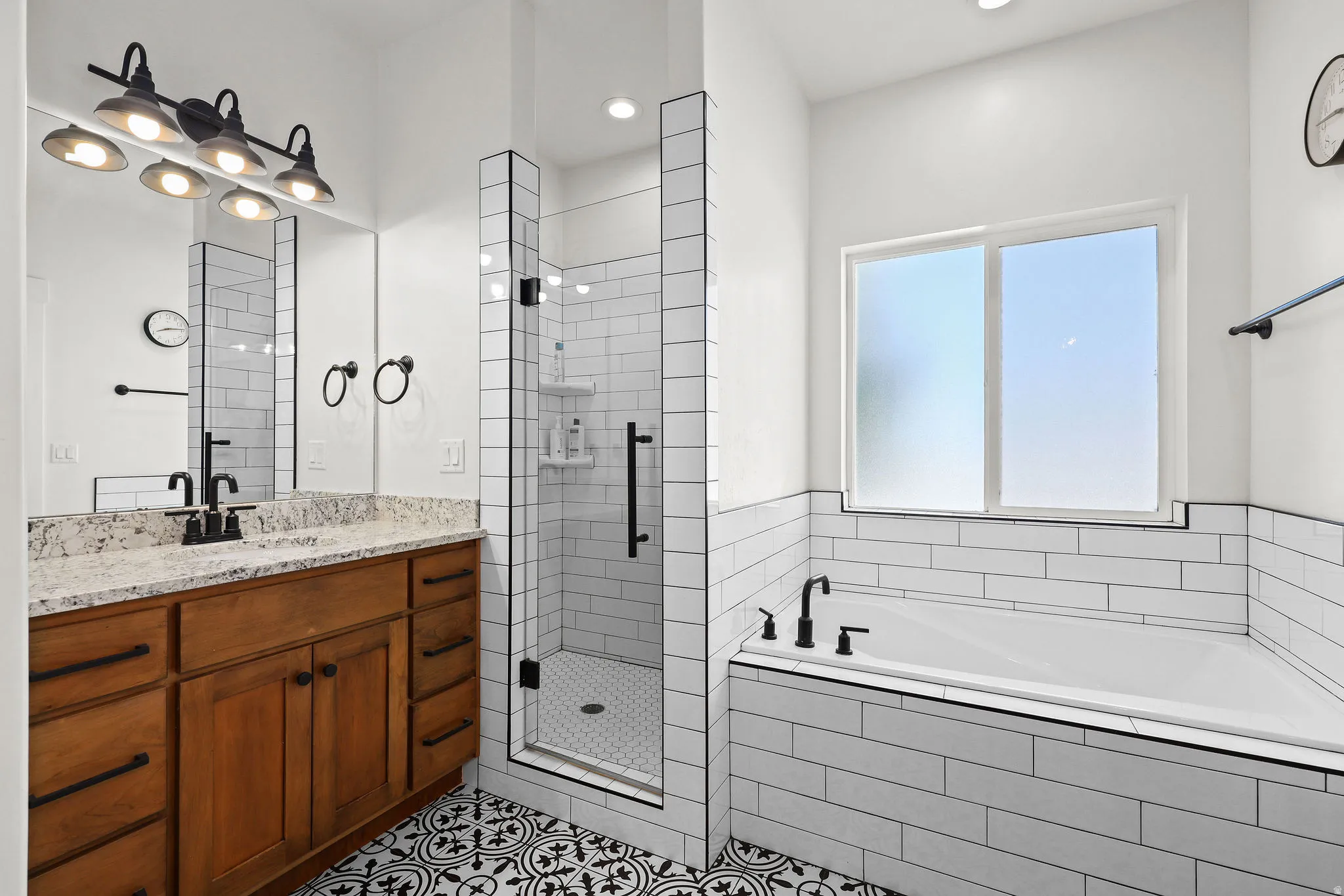 Bathroom featuring a wooden vanity with a stone countertop, dual sinks, and matte black fixtures