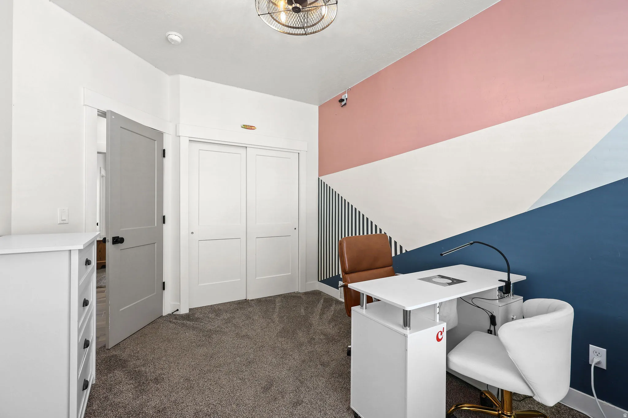 Carpeted room with a geometric accent wall featuring pink, white, and blue tones