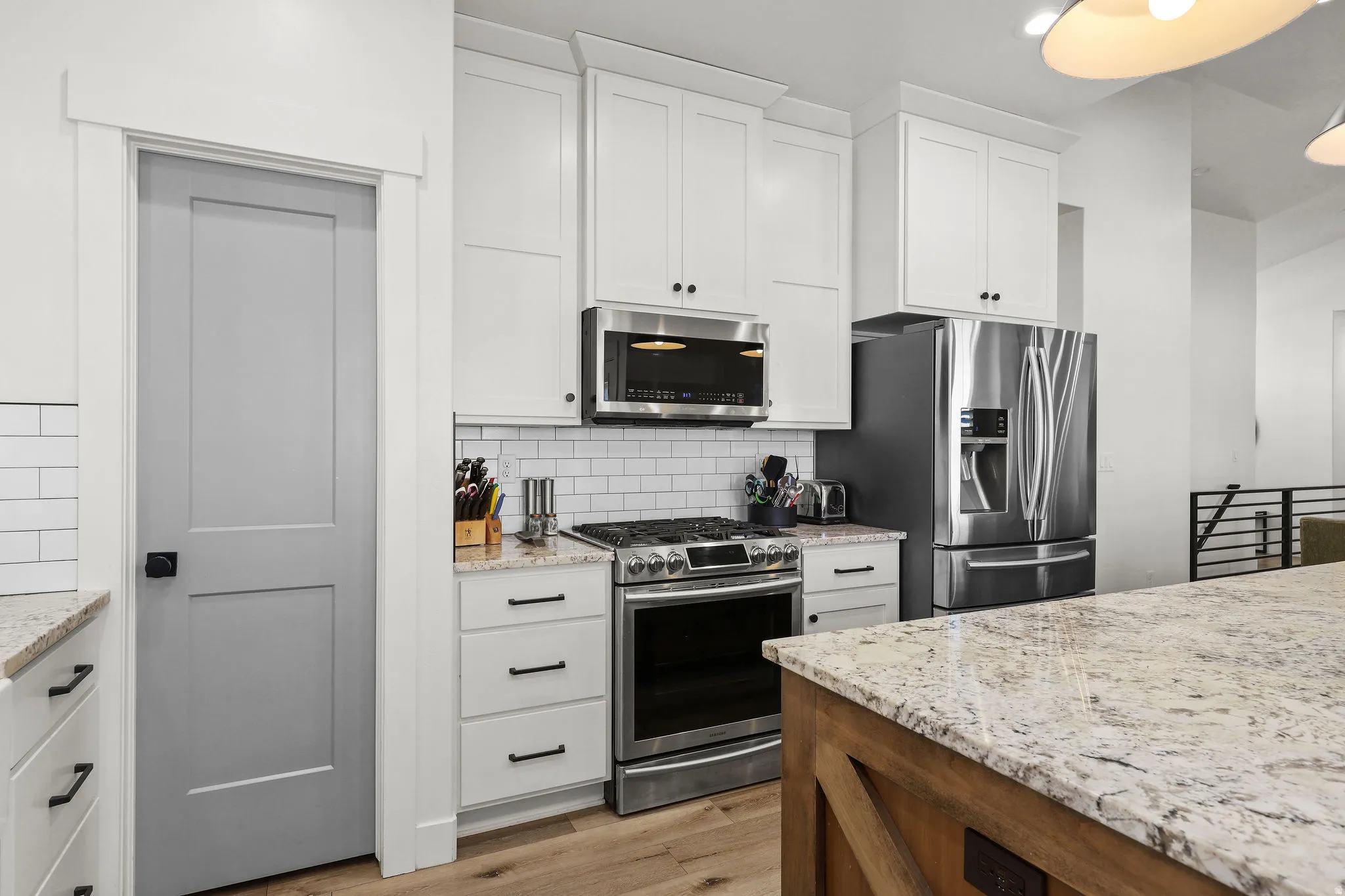 Kitchen featuring white shaker cabinetry, stainless steel appliances, granite countertops, and subway tile backsplash