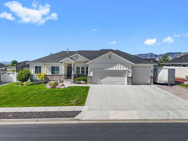 Modern ranch-style home featuring a stone and board-and-batten facade, multiple garages, and a manicured front lawn