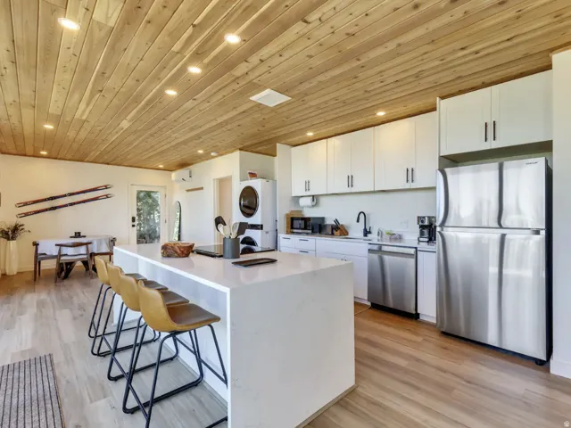 Modern kitchen and dining area featuring a wood-plank ceiling, recessed lighting, and light wood-finish flooring
