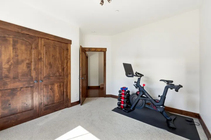 Room featuring double arched panel wood doors, an open wood doorframe, light-colored carpeting, and white walls