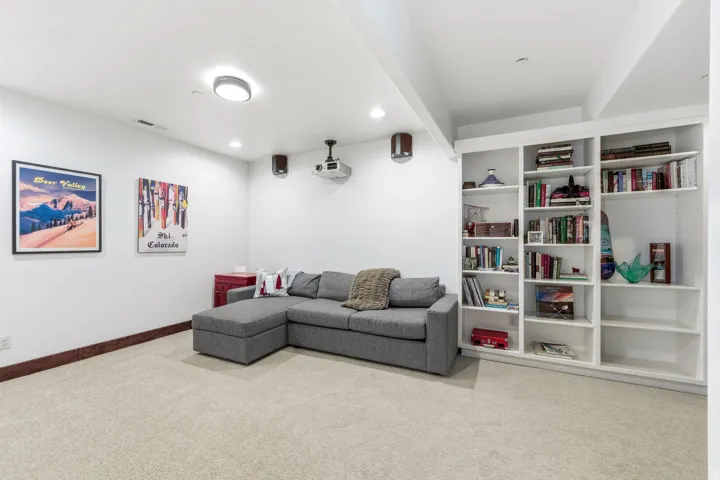 Spacious room featuring neutral carpet flooring, recessed lighting, and a full-wall built-in bookcase