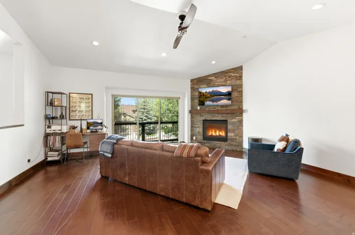 Spacious living area featuring rich wood-finish flooring, a vaulted ceiling, and recessed lighting