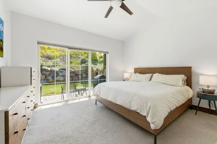 Vaulted ceiling room with large sliding glass door, direct patio access, and a ceiling fan