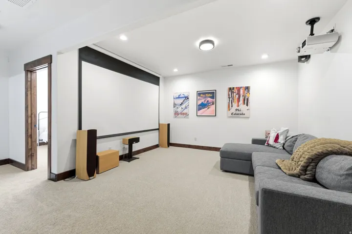 Entertainment room featuring a large projection screen, recessed lighting, and soft carpet flooring