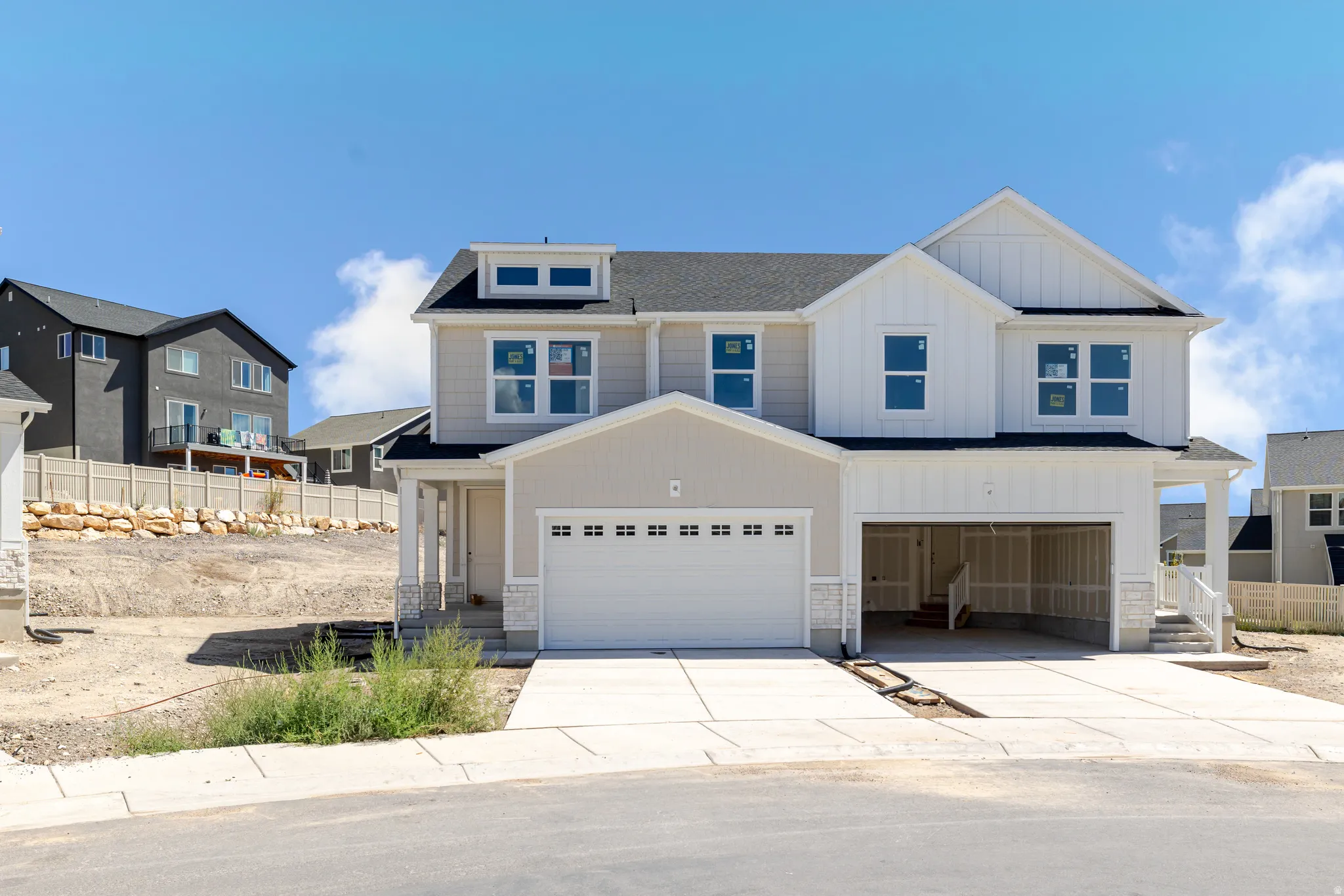 Modern exterior with light-toned siding, stone accents, and a dark roof