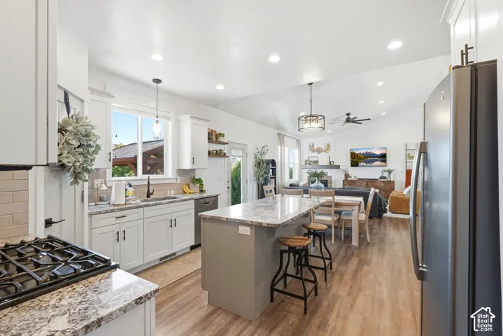 Open-concept kitchen featuring an island with counter seating, granite countertops, and wood-finish flooring