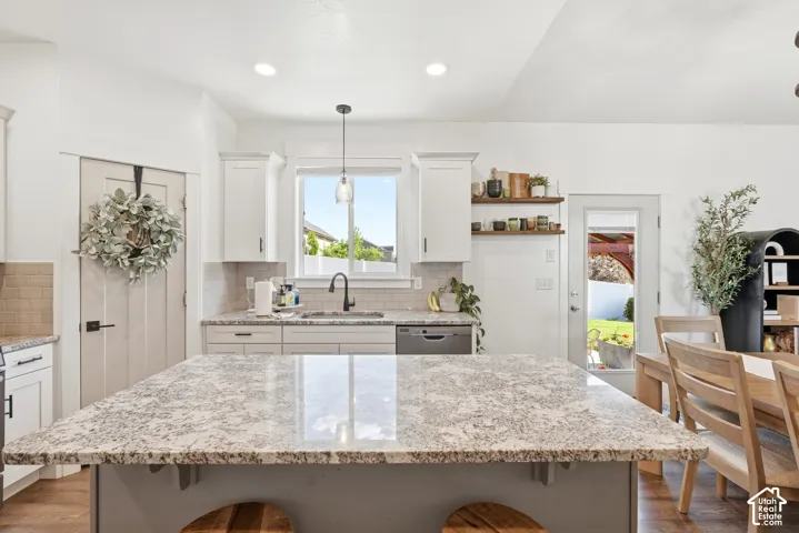 Expansive kitchen island with a speckled stone countertop, surrounded by white cabinetry and a subway tile backsplash