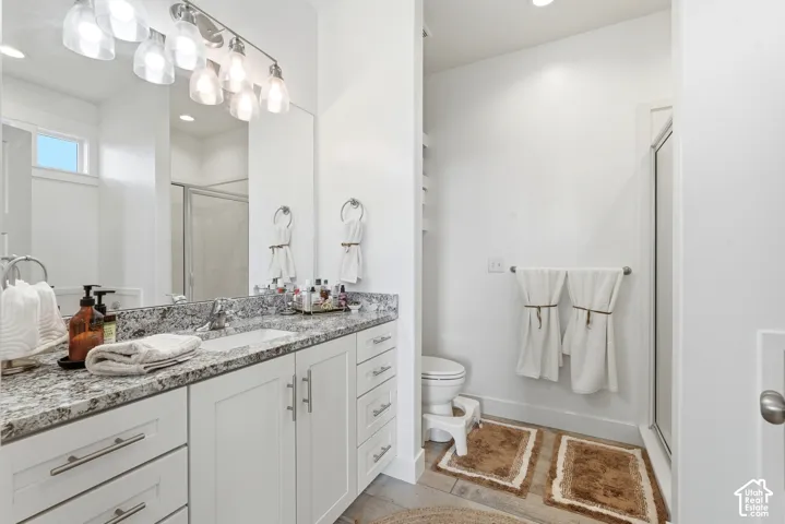 Bathroom featuring a double vanity with stone countertops, undermount sinks, and white shaker-style cabinetry