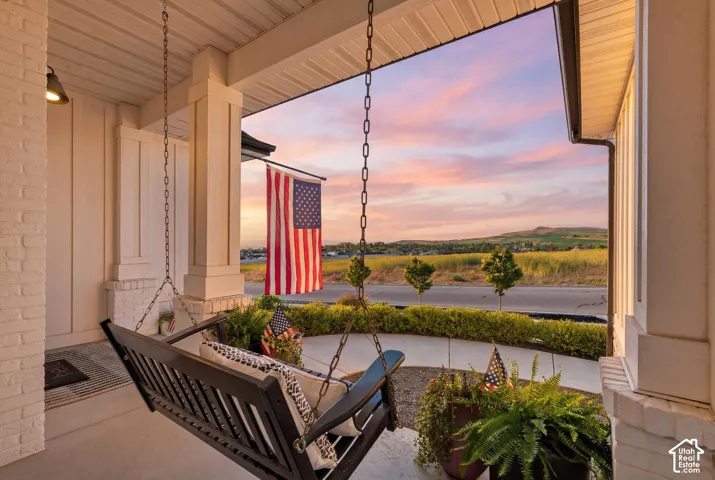 Covered front porch featuring a porch swing, white brick, and board and batten siding