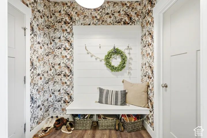 Entryway mudroom bench with built-in storage cubbies, shiplap wall paneling, and floral wallpaper