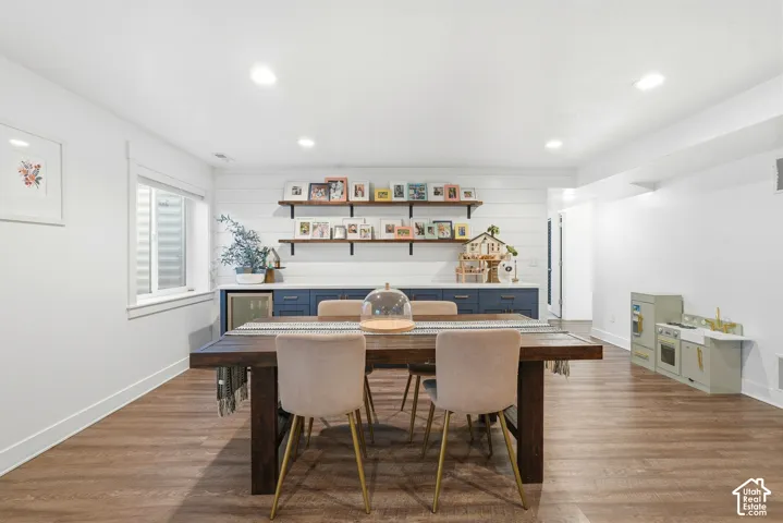 Spacious room featuring wood-finish flooring, a built-in cabinetry system with open shelving, recessed lighting, and a window with blinds