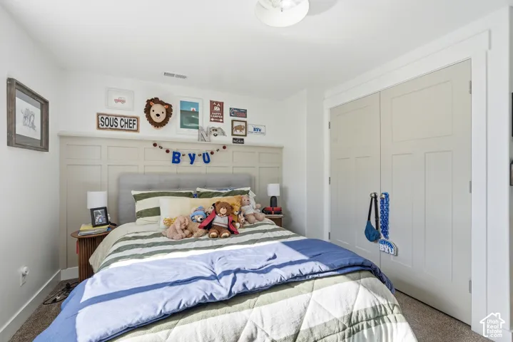 Bedroom featuring a paneled accent wall, neutral carpeting, and a built-in closet with two-panel doors and white trim