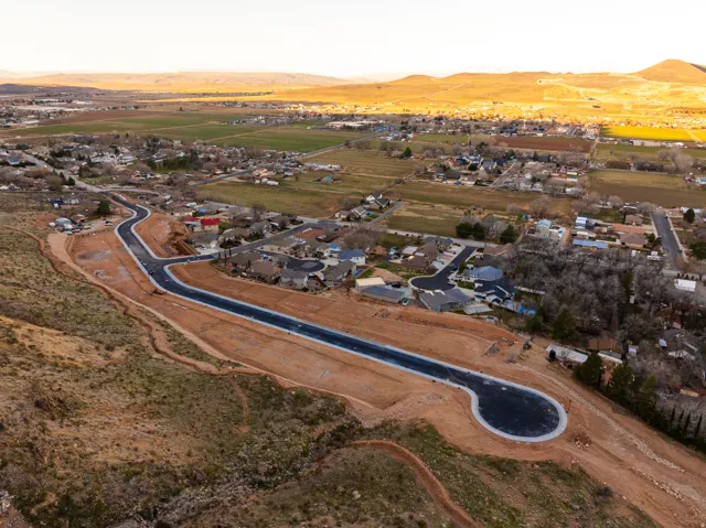 Aerial perspective showcasing a newly paved road with a cul-de-sac, surrounded by graded building lots and existing residential areas