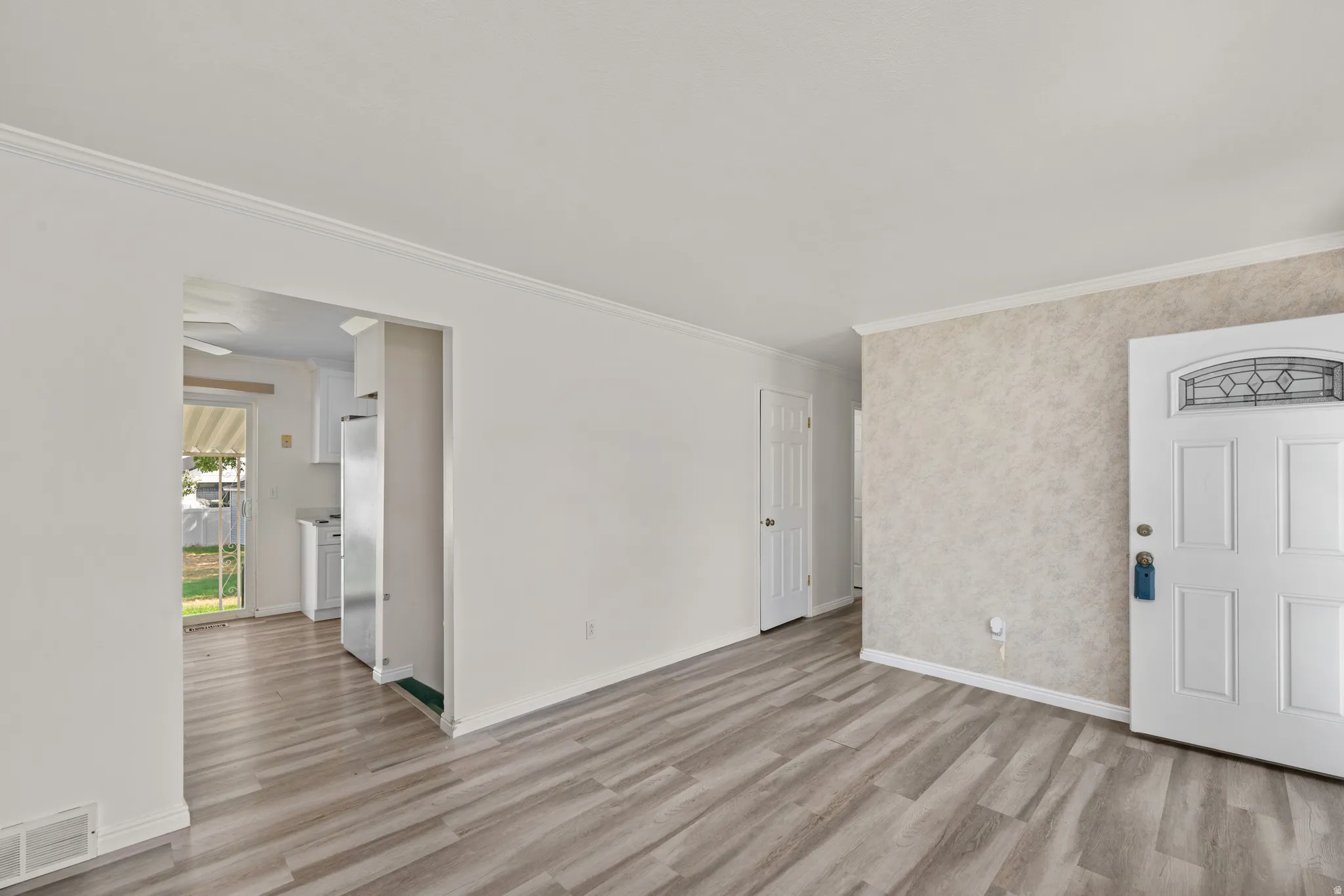 Spacious living area featuring wood-finish flooring, white baseboards, and crown molding