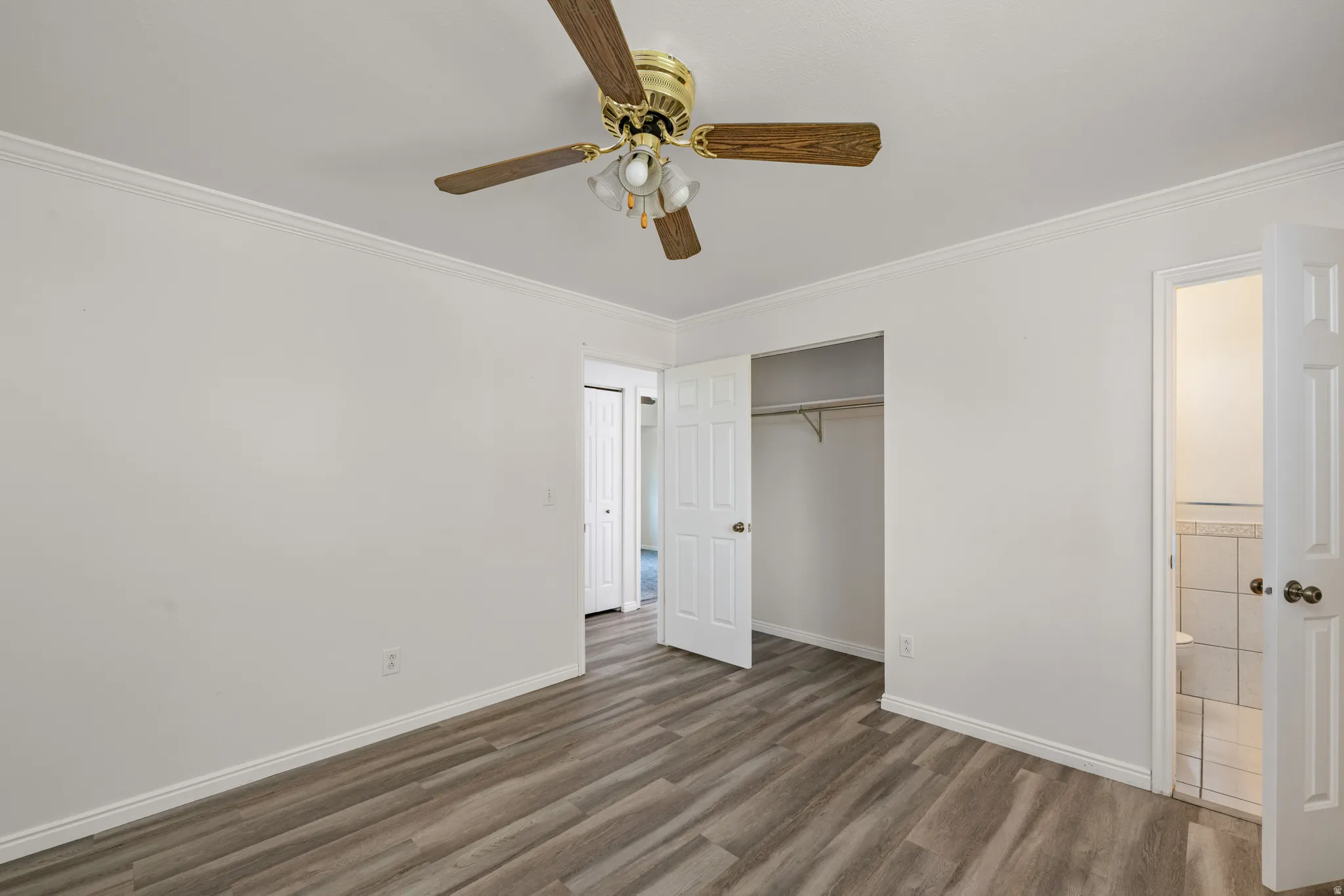 Room featuring wood-finish flooring, white walls, and crown molding
