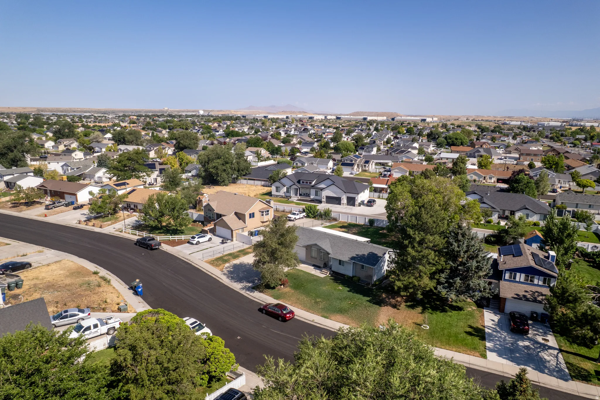Expansive aerial view showcasing a developed residential neighborhood with mature trees and varied architectural styles