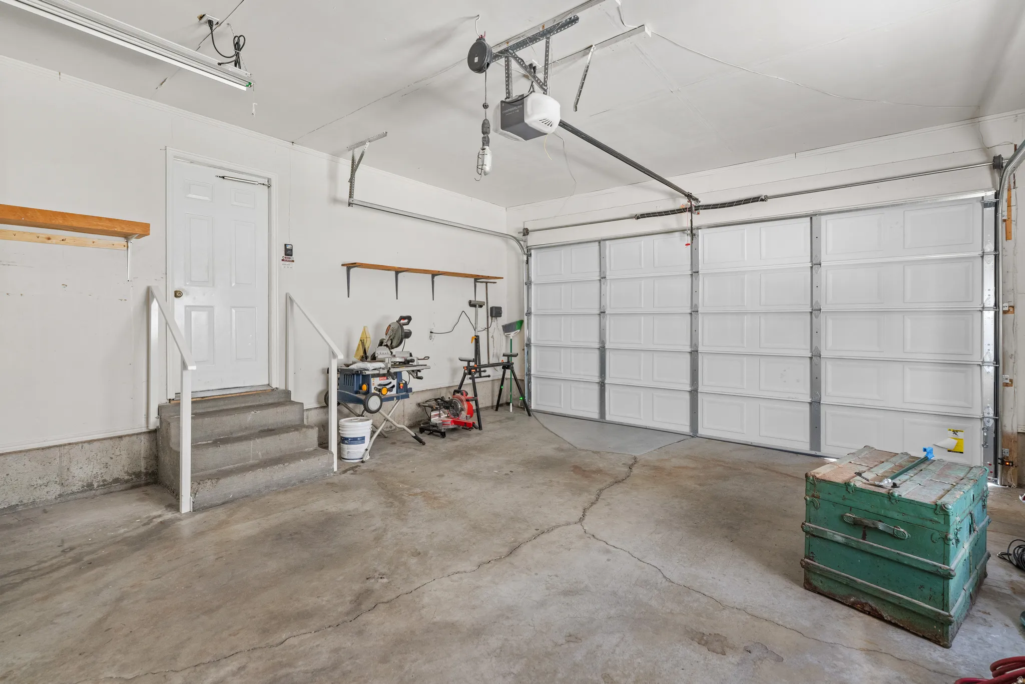 Spacious garage featuring a concrete floor, overhead fluorescent lighting, and a paneled garage door