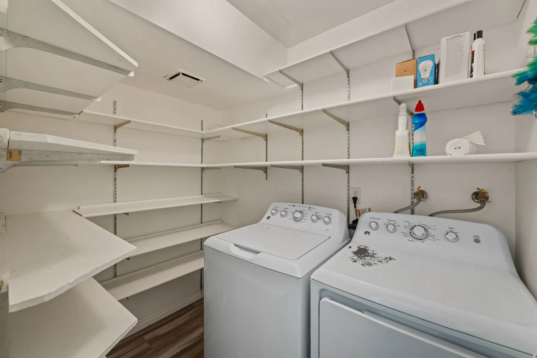 Dedicated laundry area featuring a washer and dryer, extensive built-in shelving, white walls, and wood-finish flooring
