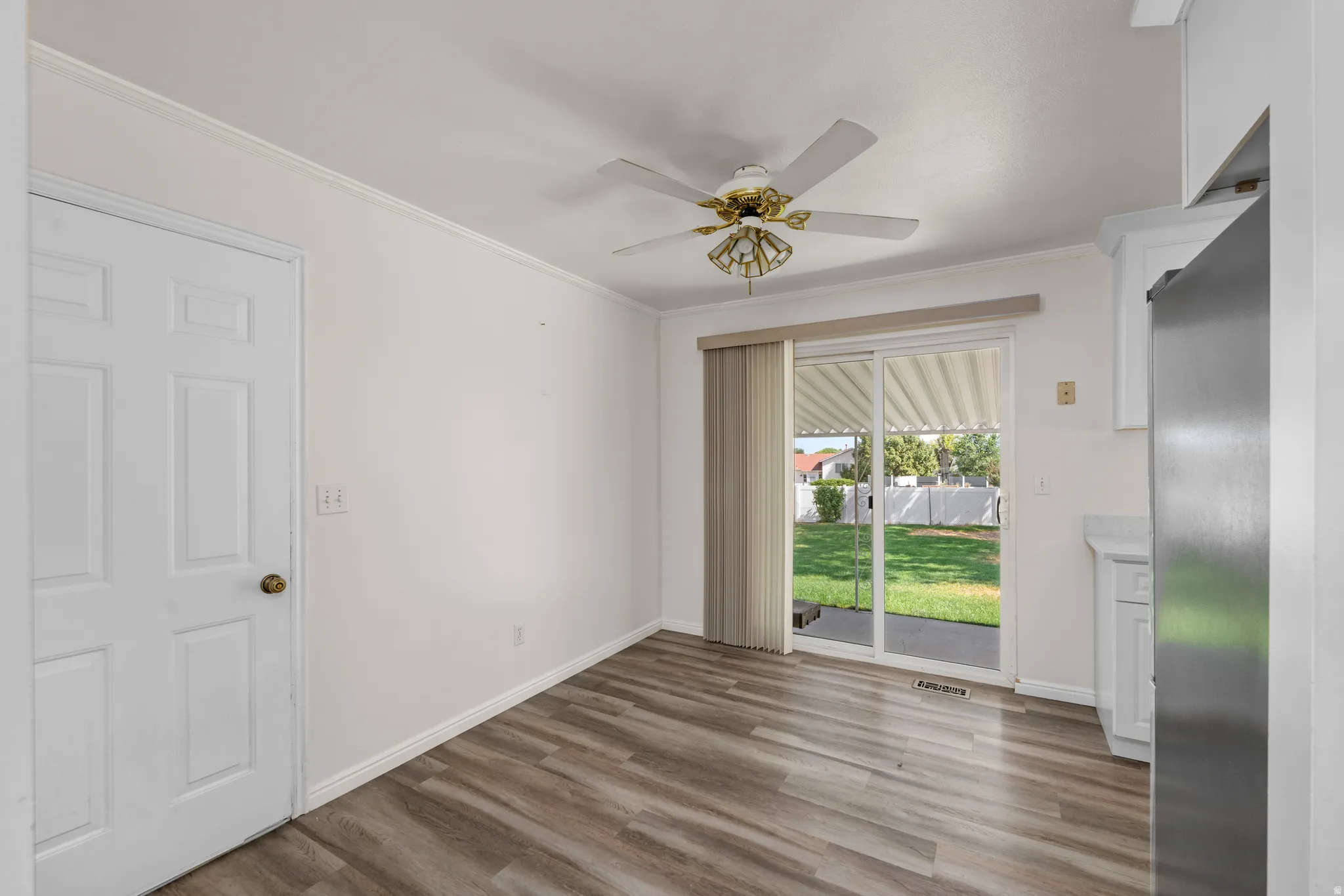 Dining area featuring wood-finish flooring, white walls, and a ceiling fan with integrated lighting