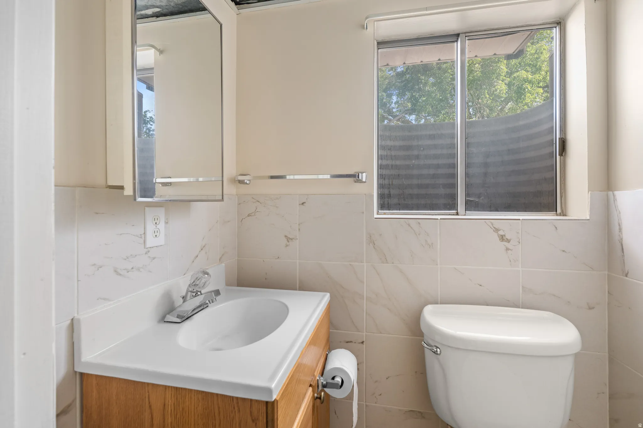 Bathroom featuring a wood-finish vanity with an integrated sink and chrome faucet, complemented by a medicine cabinet