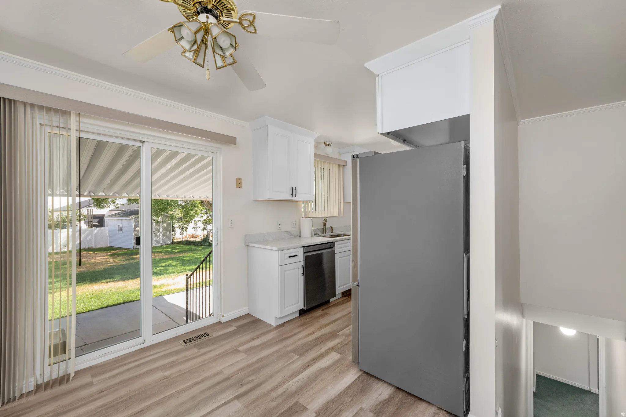 Kitchen area featuring wood-finish flooring, white cabinetry with dark hardware, and light-toned countertops