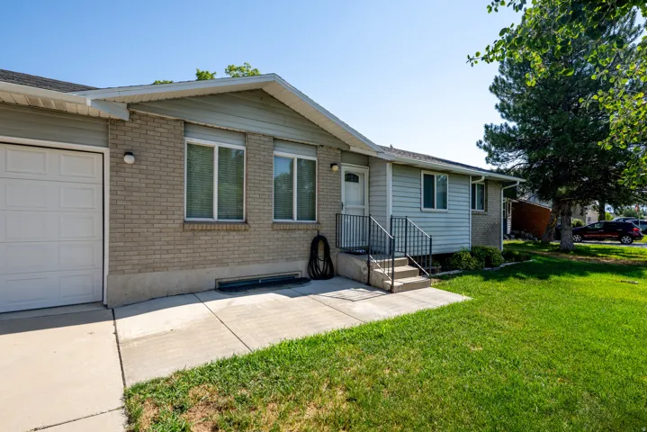Exterior featuring a white garage door, light brick facade, siding accents, and a concrete patio
