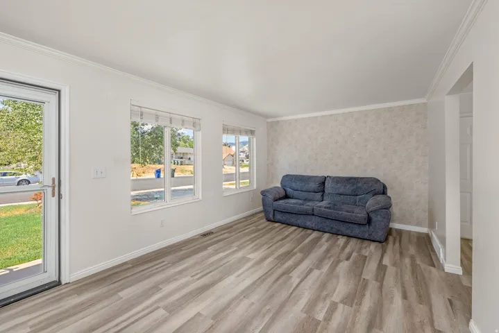 Bright living area featuring wood-finish flooring, a textured accent wall, and multiple windows with blinds