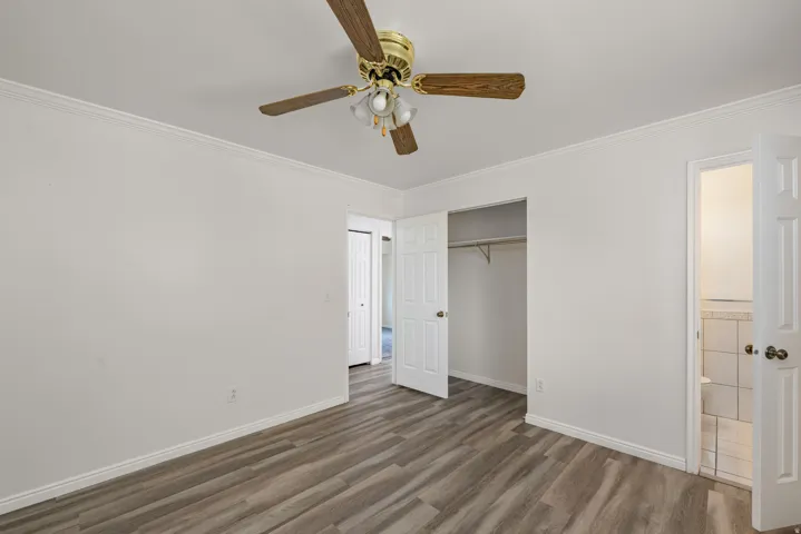 Room featuring wood-finish flooring, white walls, and crown molding