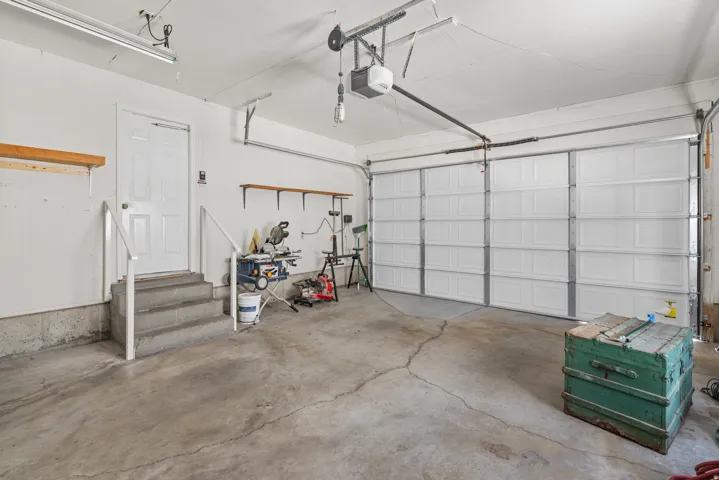 Spacious garage featuring a concrete floor, overhead fluorescent lighting, and a paneled garage door