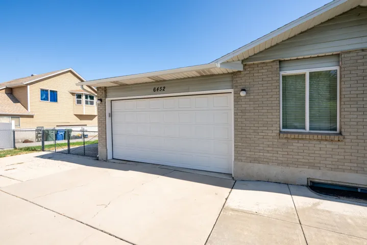 Attached garage with a white panel door, light brick exterior, and concrete driveway