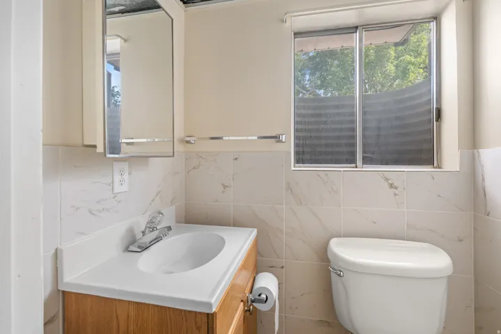 Bathroom featuring a wood-finish vanity with an integrated sink and chrome faucet, complemented by a medicine cabinet