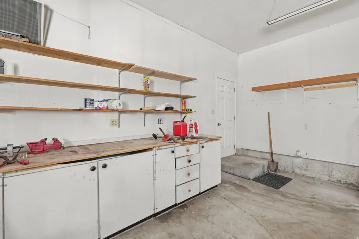 Garage workshop featuring extensive built-in cabinetry, durable concrete flooring, and multiple wood-finish shelving units for organized storage