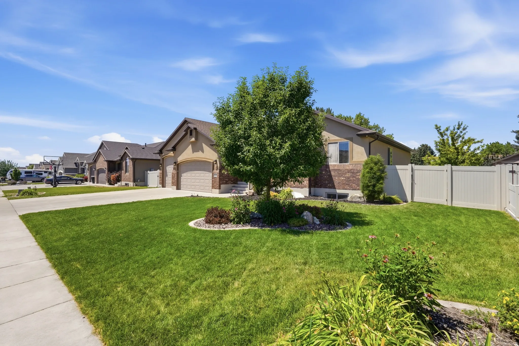 Single-story residence featuring a brick and stucco exterior, an attached two-car garage, and a landscaped front yard with mature trees