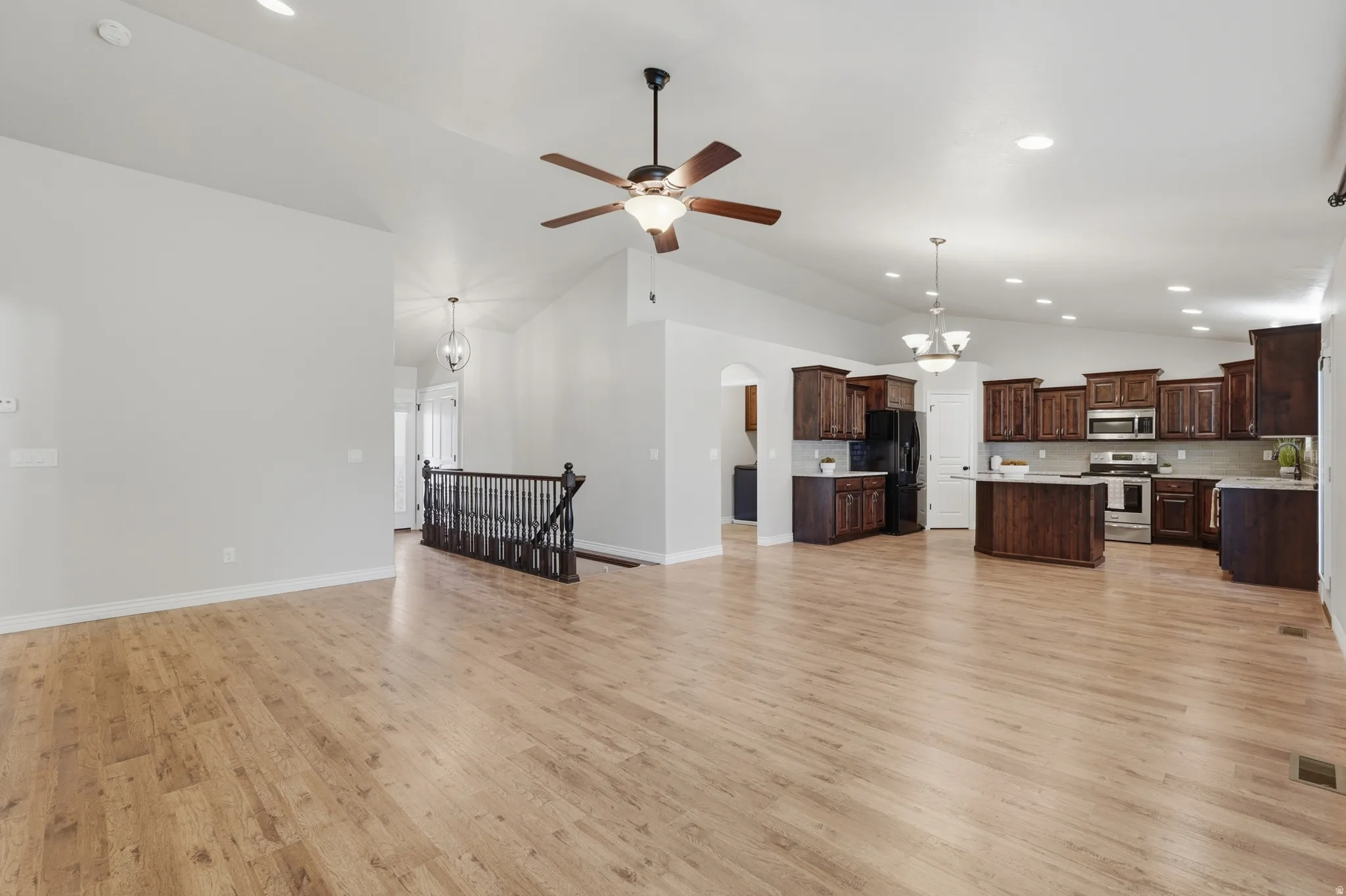 Expansive open-concept living area featuring light wood-finish flooring, vaulted ceilings, and recessed lighting