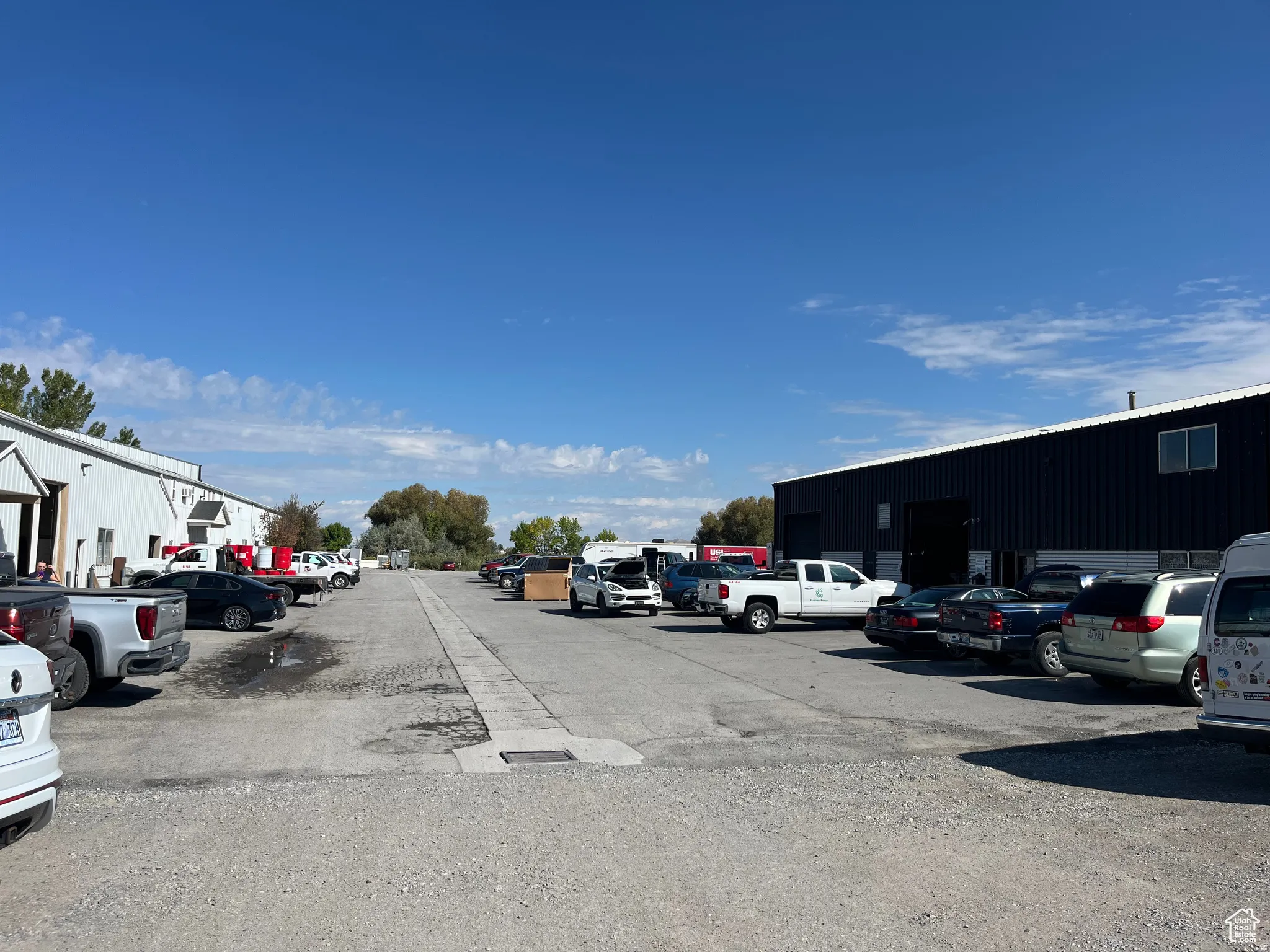 Expansive gravel parking area bordered by two industrial structures