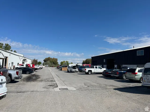 Expansive gravel parking area bordered by two industrial structures