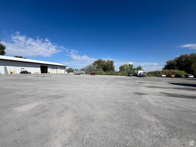 Expansive gravel lot with a large industrial building featuring a white facade and multiple bay doors